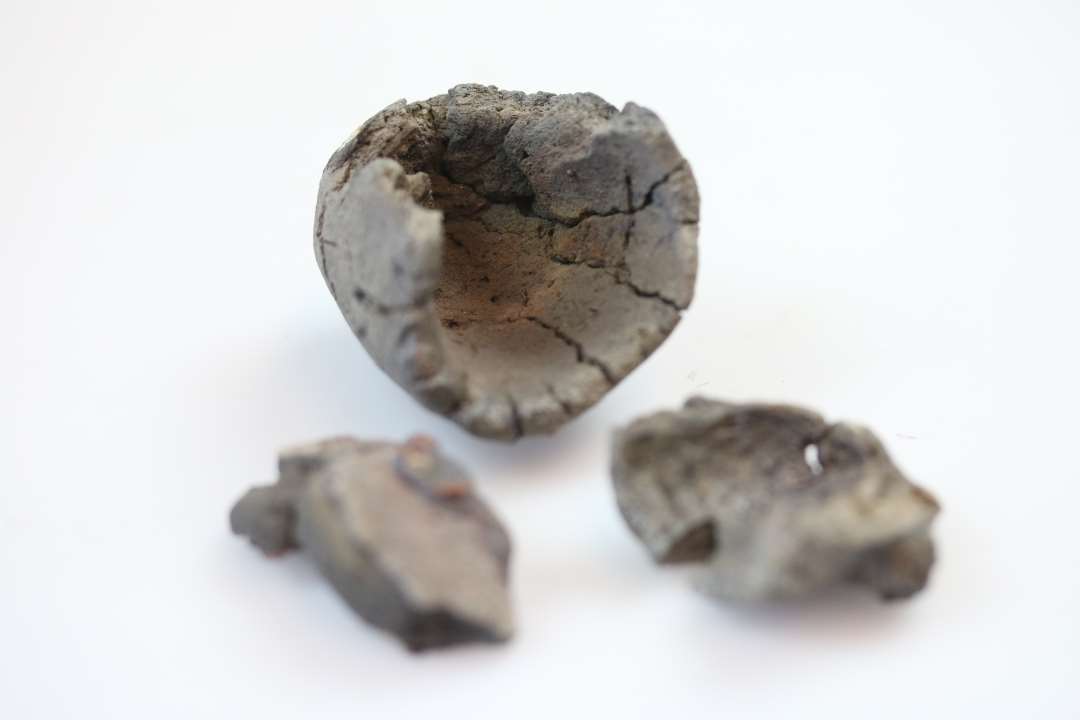 Dele til en digel og rester af yderlig en eller flere�den ene m�ler:�h�j 4,5 cm�diam. 3,5 cm�fastsmeltet slagge og rest af v�vning